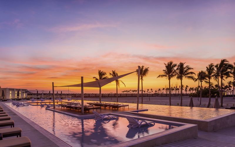 Poolen og smuk solnedgang på Fanar Hotel & Residences i Salalah, Oman.
